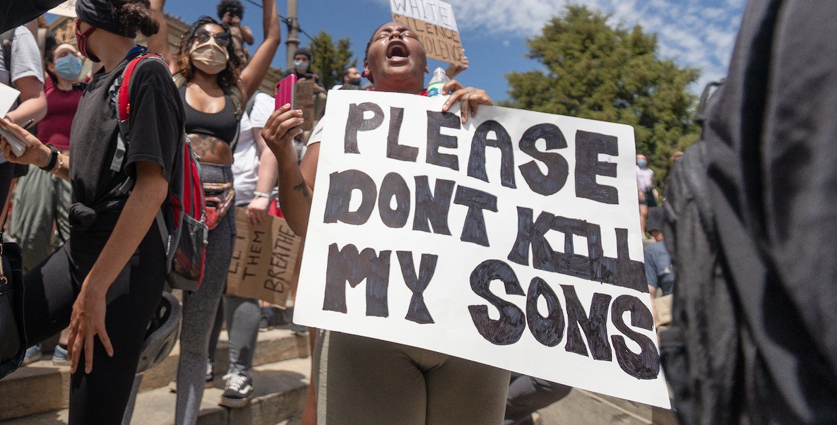 A woman holds a sign during a protest following the death of George Floyd that reads, "Please don't kill my son."