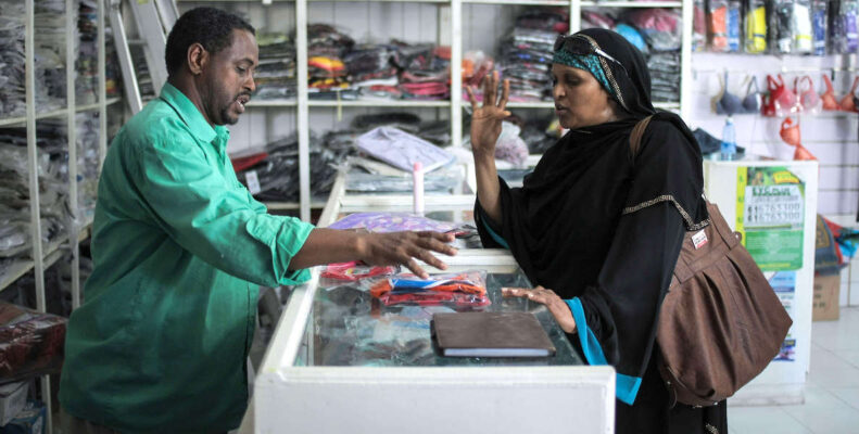 A black small business owner helps a customer pick out some goods for her home.
