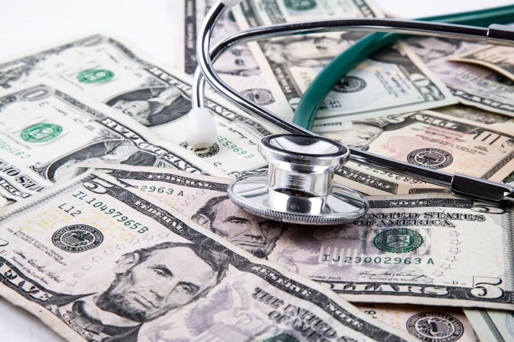 stethoscope on pile of money, cost of healthcare