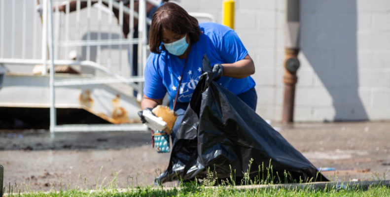 A woman picks up trash in her neighborhood, volunteering like a champ