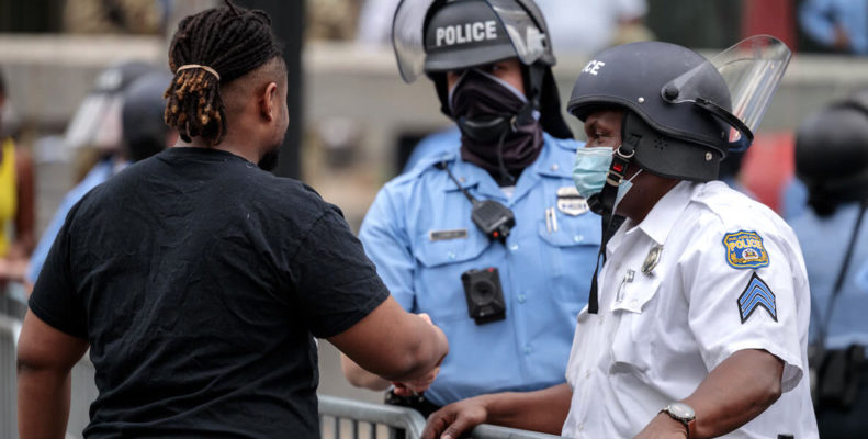 A Black Lives Matter protestor shakes hands with Philadelphia police officers in a show of peace and solidarity.