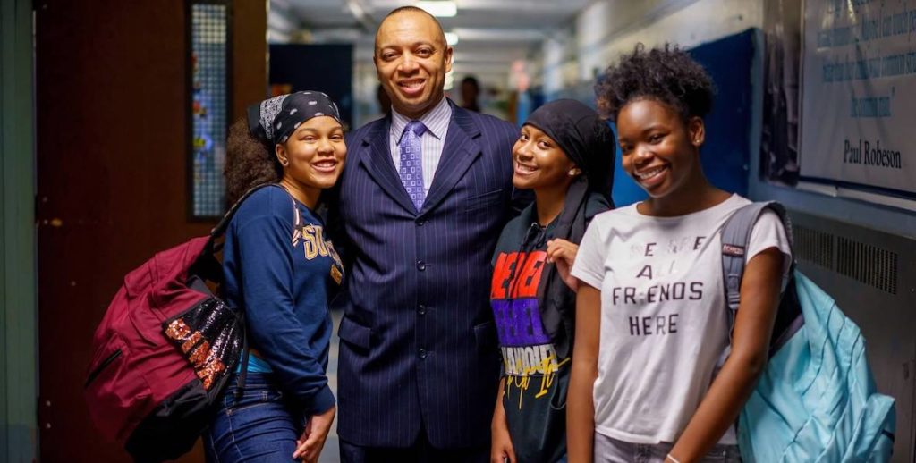 Richard Gordon, principal of Philadelphia's Robeson High School, poses with students in the hallway.