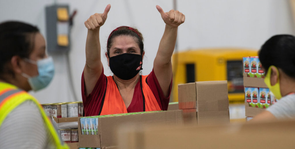 A small business factory worker wearing a mask during Covid-19 gives a thumbs up during the pandemic