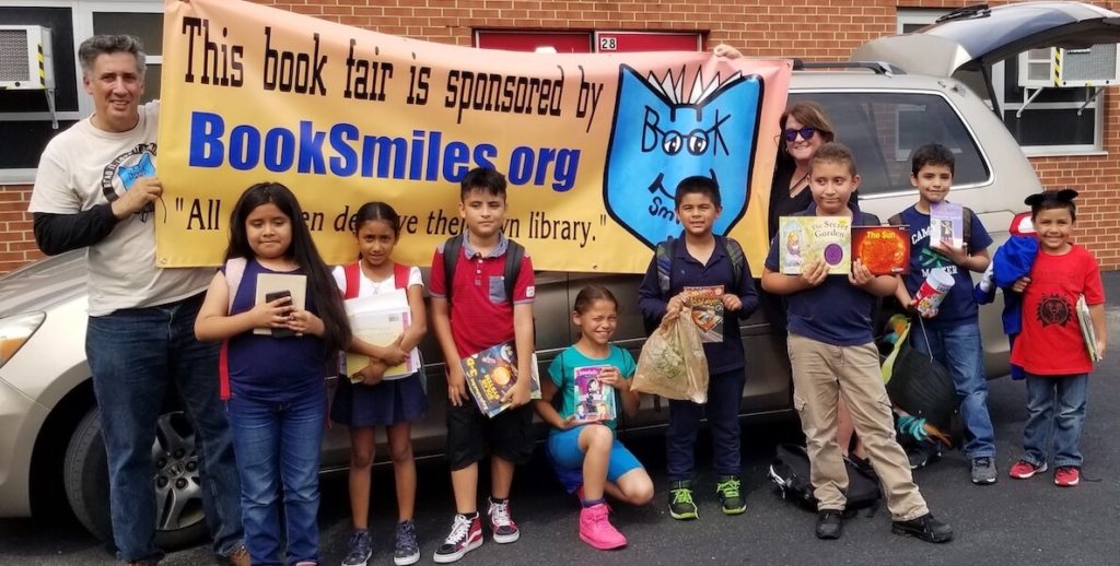 Larry Abrams, owner of BookSmiles, poses with school children who received free books