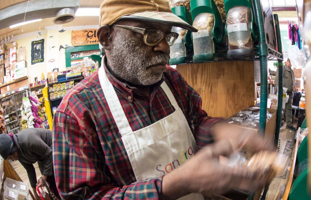 A black business owner checks on his stock of bulk produce.