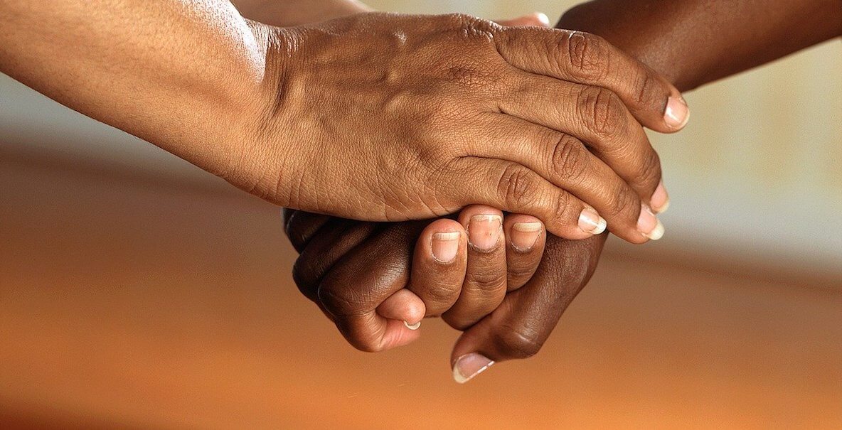 Black and brown hands clasped in support