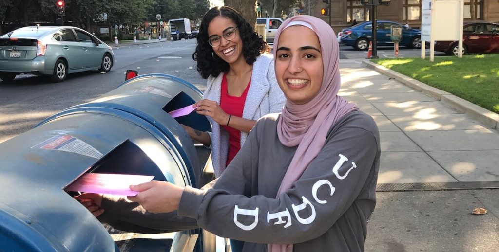 Two women drop their ballots in the mailbox before Election Day 2020