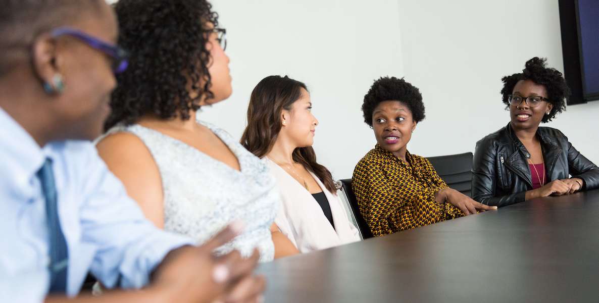 Five diverse people in a boardroom discuss important matters for their business