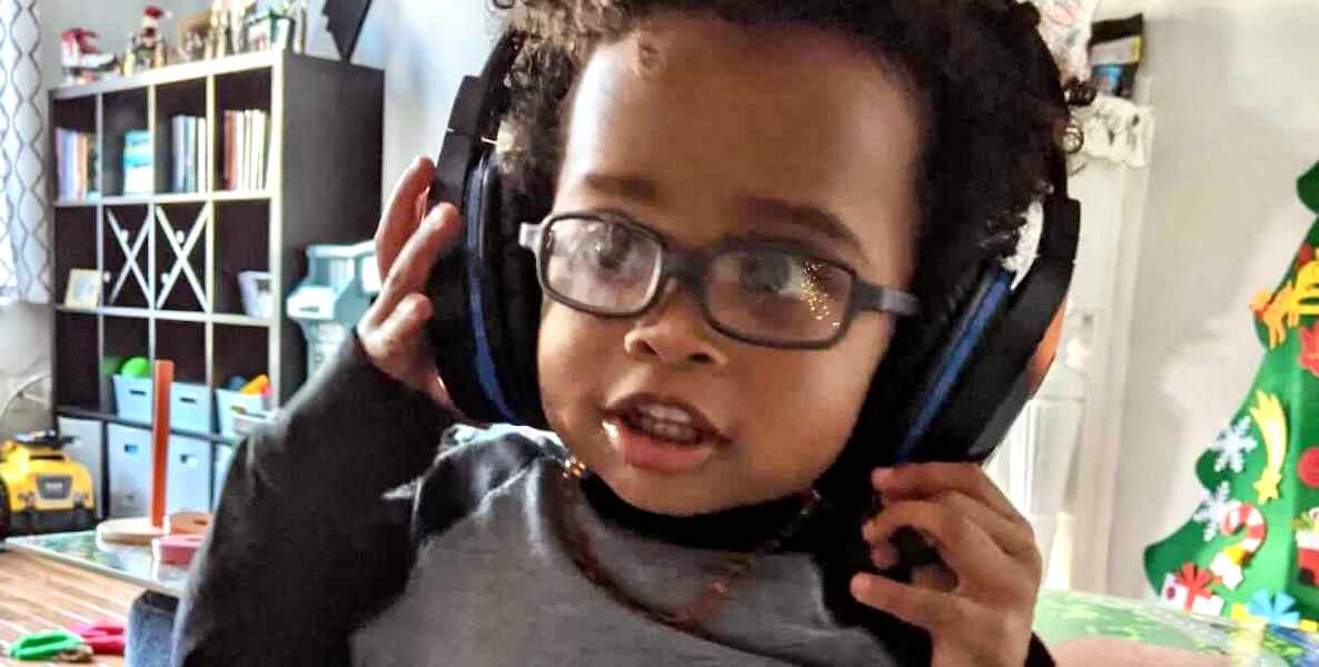 A child involved in Lullaby Project Philadelphia listens to a song its parents wrote through a giant pair of headphones.