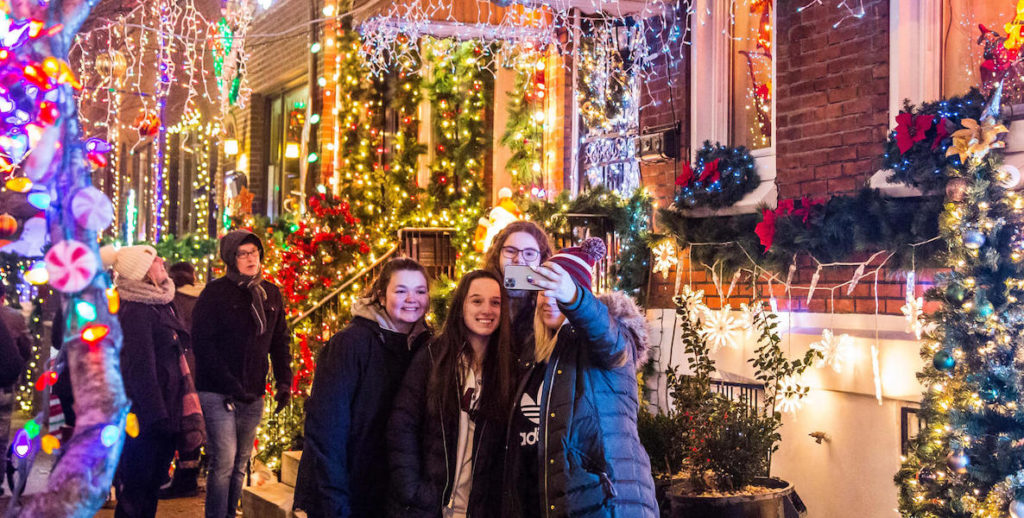Friends take a selfie in front of the dazzling holiday light show at The Miracle on 13th Street in South Philadelphia
