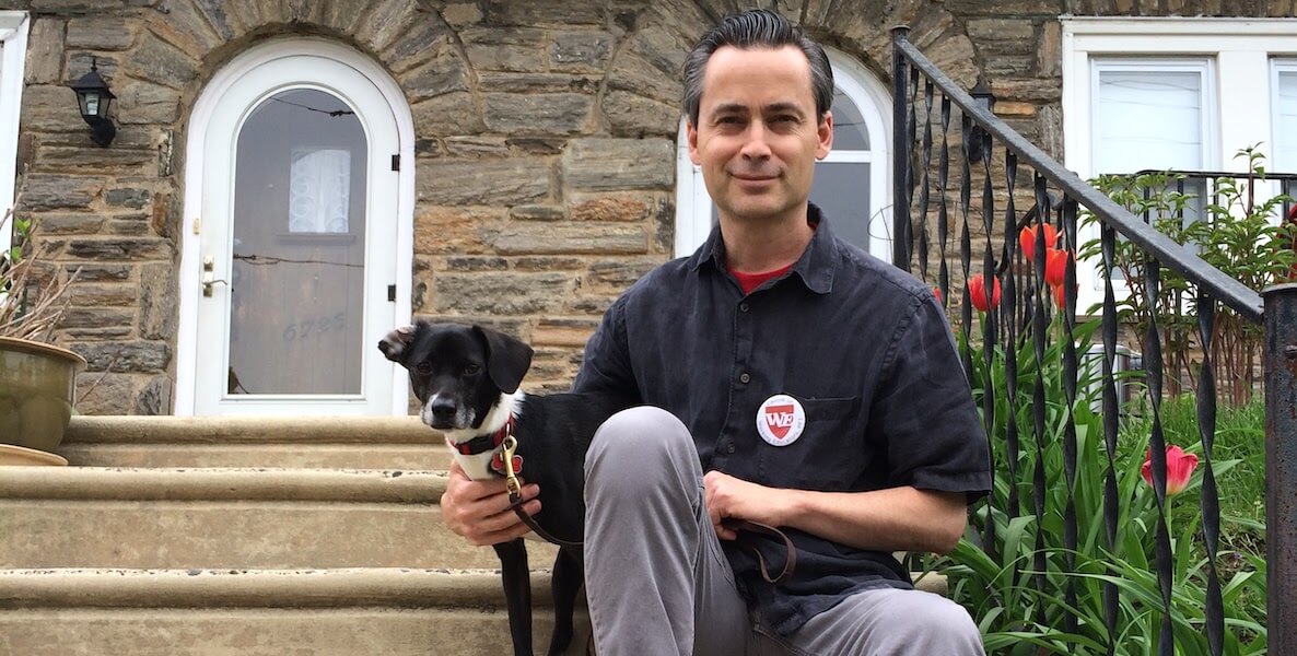 Philadelphia teacher and 2020 Integrity Icon Thomas Quinn sits on some steps with his dog.