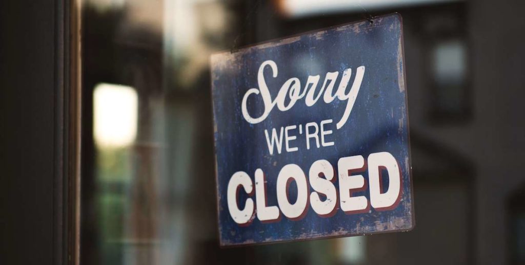A sign hanging in a store window reads "sorry, we're closed"—a familiar sight during Covid-19.