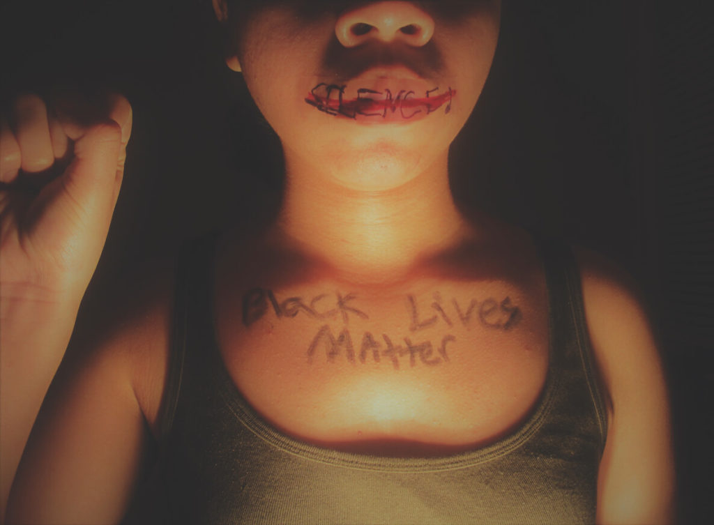 A young woman has "silence" written over her and "Black Lives Matter" written across her chest