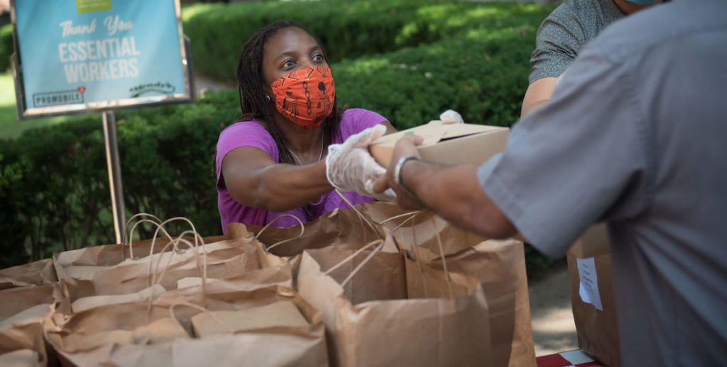 A woman hands out food donations to people in need.