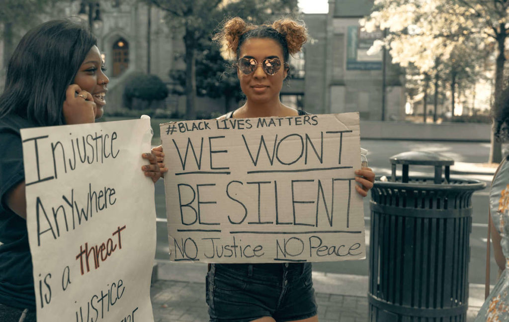 Two women hold up signs for the Black Lives Matter movement