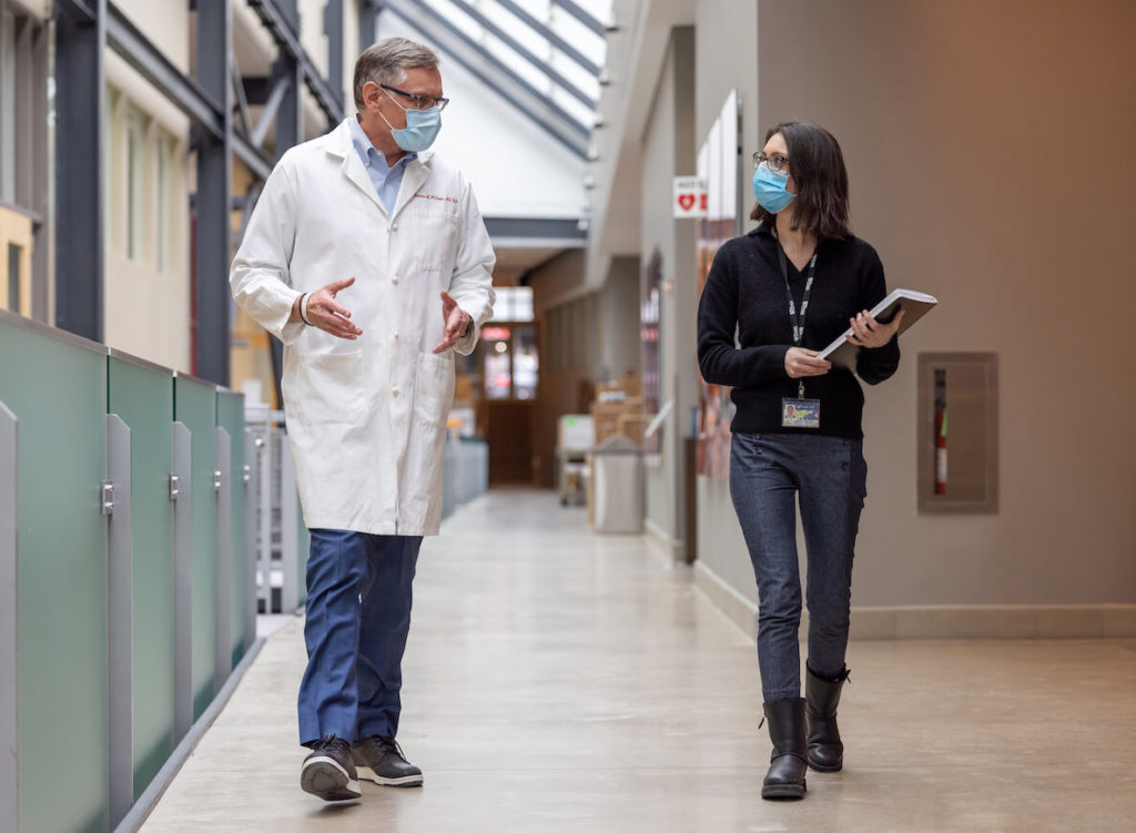 Dr. James Wilson, funder of the Orphan Disease Center at UPenn walks down a hallway with a woman