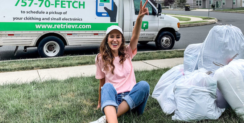 Young woman gives peace sign while sitting on her lawn with trash bags full of clothes and electronics to donate through Retrievr