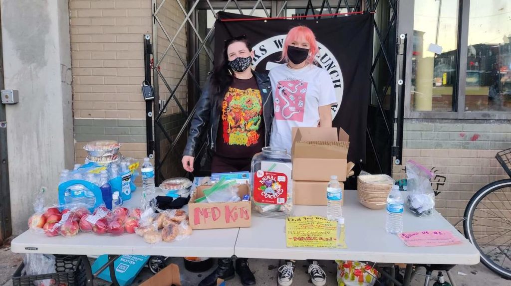 Members of South Philly Punks With Lunch man a table for the homeless.