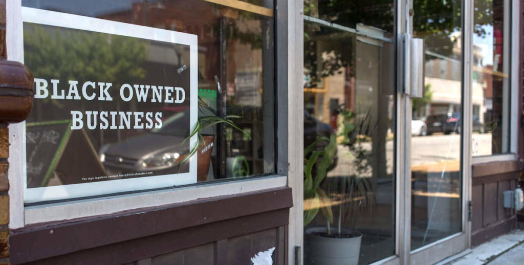 A sign in a shop window reads "black owned business"