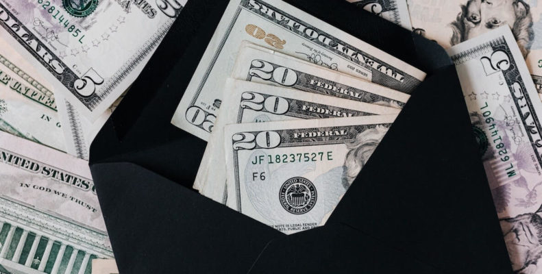 20 dollar bills in black envelope with five dollar bills in background