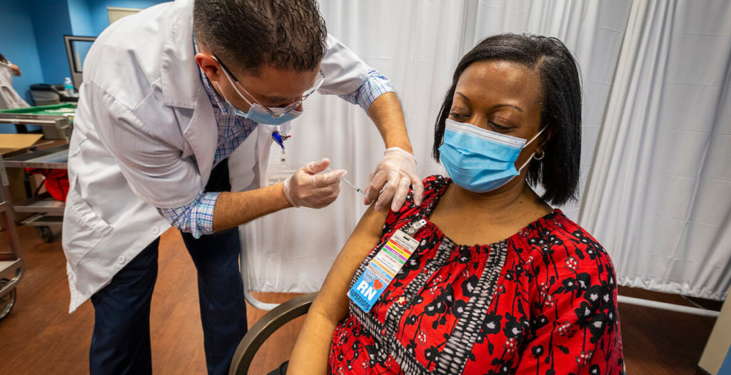 Black woman wearing mask gets Covid-19 vaccine