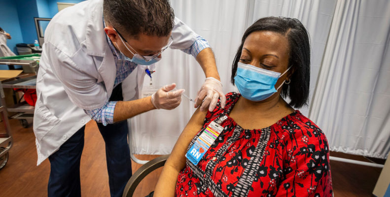 Black woman wearing mask gets Covid-19 vaccine