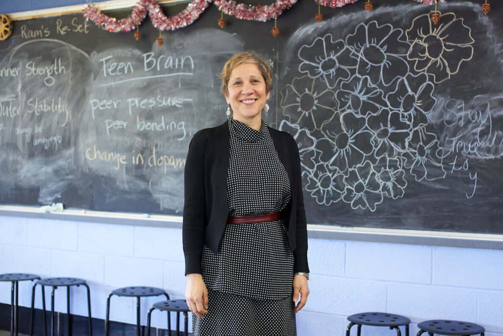 Amy Edelstein stands in front of chalkboard in a classroom