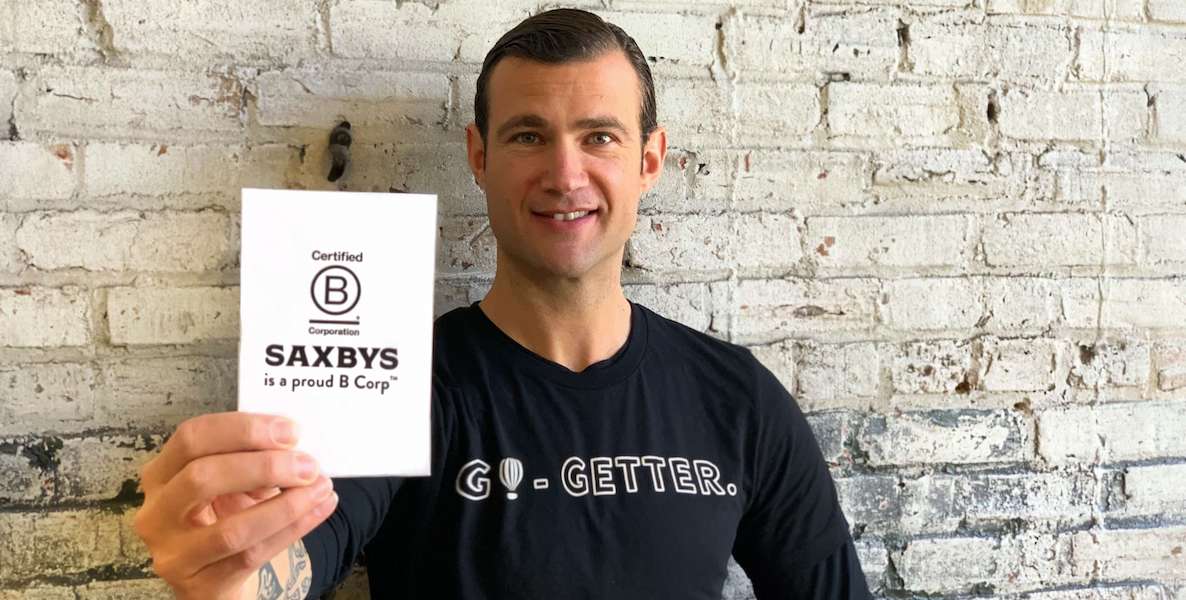 Saxbys owner and founder Nick Bayer holds a card showing his company's B Corp status