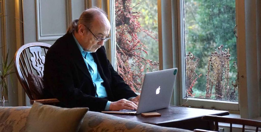 An older man sits at his computer to take a session with Teens Teach Technology
