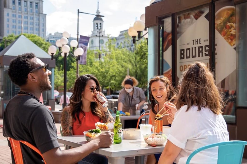 Friends hangout on the patio of The Bourse Food Hall in Old City Philadelphia