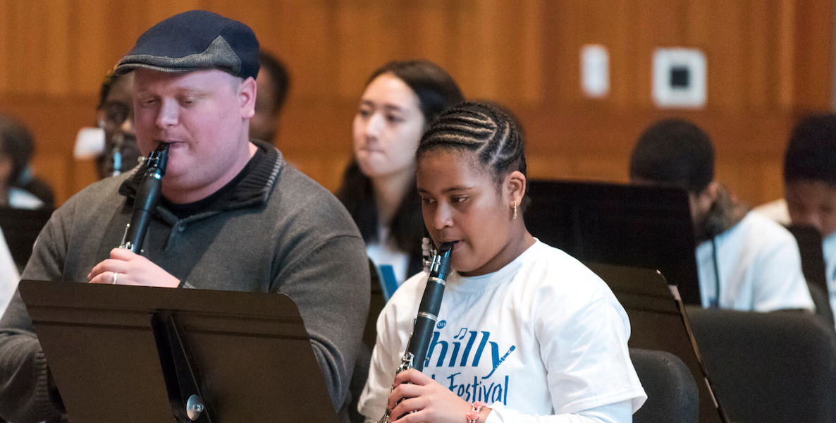 A young woman involved in Philly arts project Young At Art plays a flute next to her mentor
