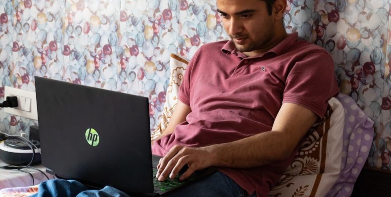 Man working at home in bed with laptop