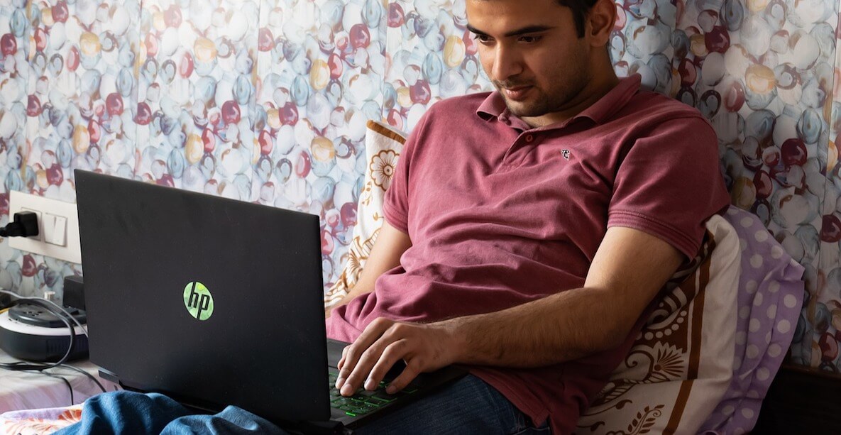 Man working at home in bed with laptop