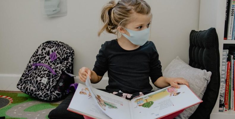 little girl reading with mask