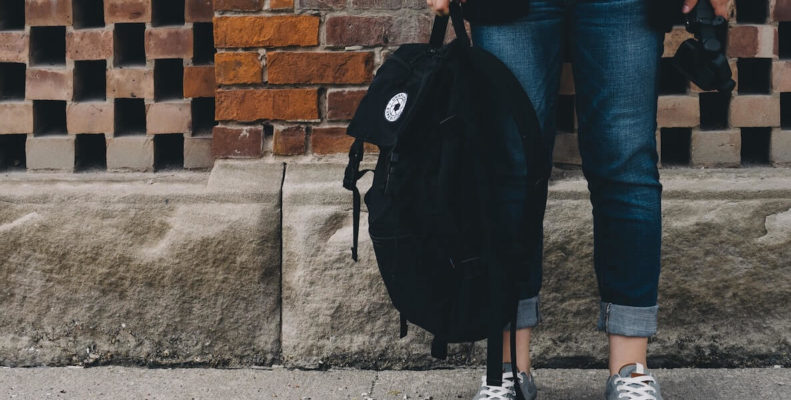 student holding backpack on sidewalk