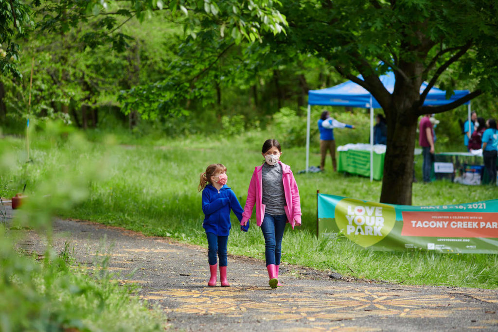 Two little girls walk hand in hand during a volunteer Love Your Park Week event