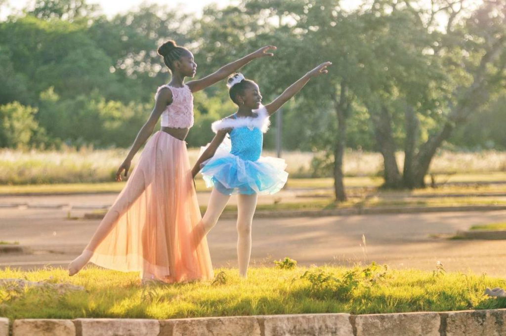 Two young girls dressed in ballet attire perform a dance