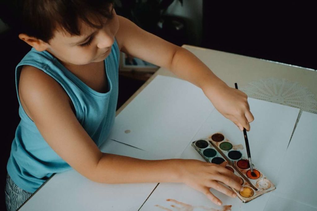 A kid uses watercolors to paint a picture 