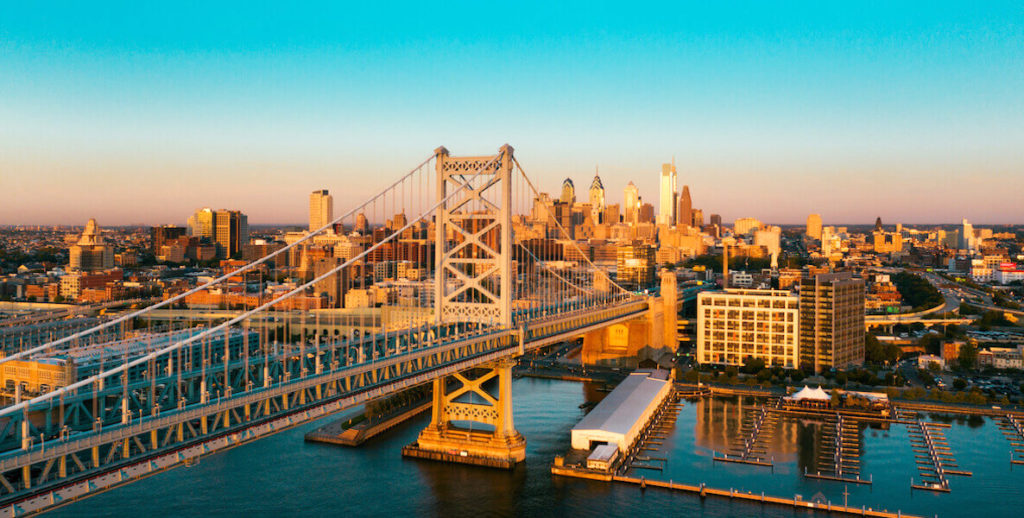 The Benjamin Franklin Bridge in Philadelphia is set against a bright blue sky.