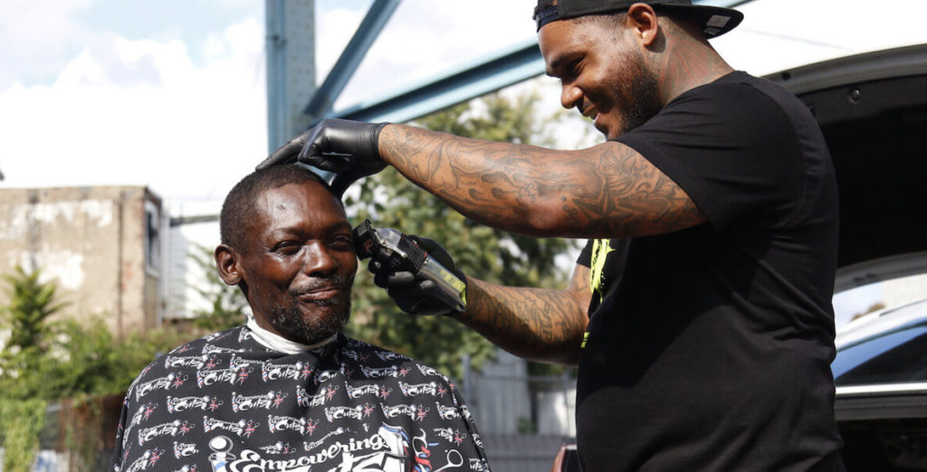 Joshua Santiago of Empowerment Cuts gives a free haircut to a man experiencing homelessness