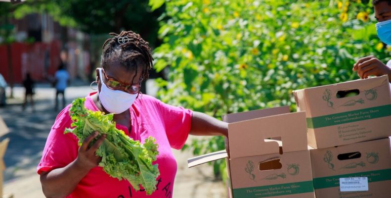 Women looks at fresh greens during pandemic food drive