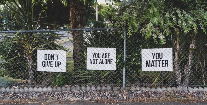 Signs about mental health line a fence.