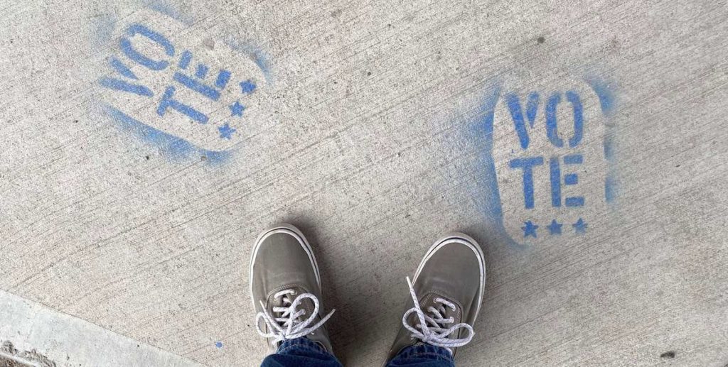 This aerial photo of sneaker'd feet standing next to "Vote" graffiti accompanies a story on primary elections