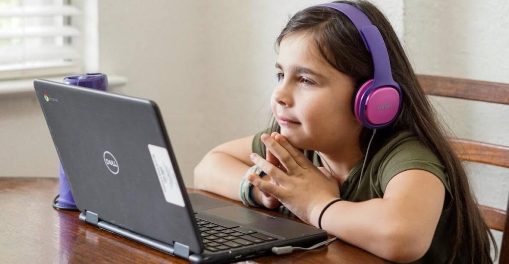 Young girl with headphones working on laptop