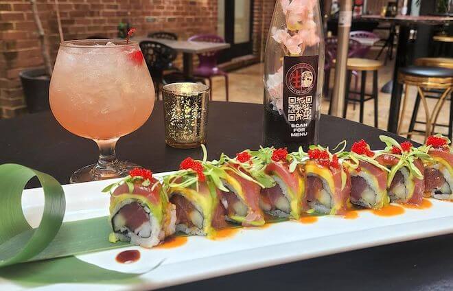 A plate of maki (sushi rolls) stands alongside a cocktail in the back outdoor lounge of 1225Raw in Philadelphia.
