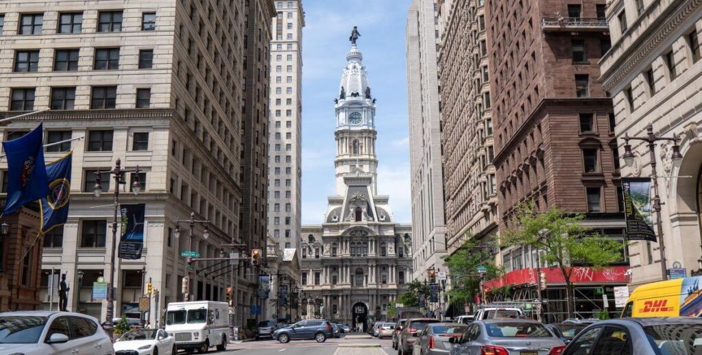 Philadelphia City Hall stands between Center City Philadelphia buildings. Below City Hall is SEPTA's City Hall Station.