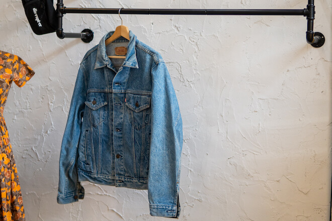 A vintage Levi's denim jeans jacket hangs on a black rack in Blk Ivy.