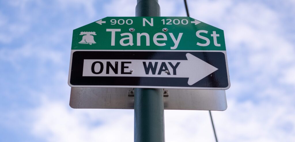The street sign for Taney Street, above a one-way sign