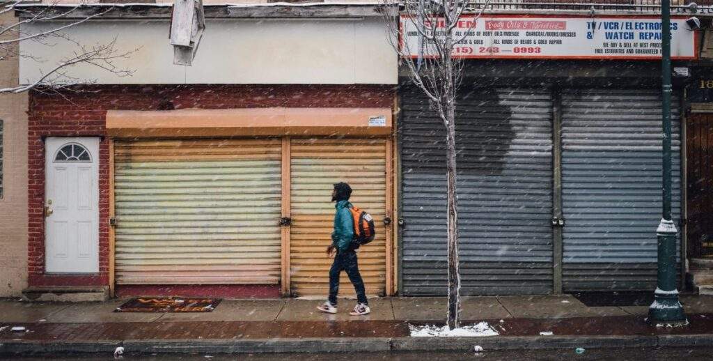 Man walks past closed shops and run-down buildings. Do the mayoral candidates have a plan for Philadelphia's poverty and inequality problems?