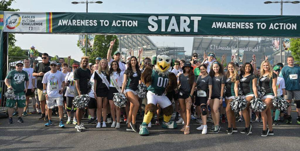 Eagles cheerleaders and Swoop, the team's eagle mascot, along with others stand at the starting line of the 2022 Eagles Autism Challenge.